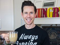 a man holding a drink in his right hand and smiling at the camera while wearing a black t - shirt that says always spring