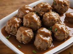 meatballs covered in gravy on a white plate