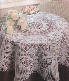 a table topped with a white doily next to a bowl of flowers on a window sill