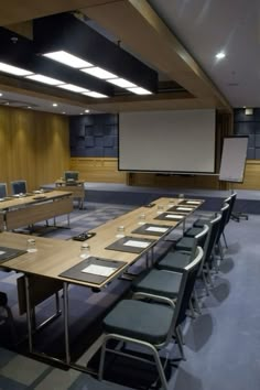 an empty conference room is set up for a meeting with chairs around the table and projector screen on the wall