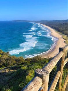 a wooden fence overlooks the beach and ocean