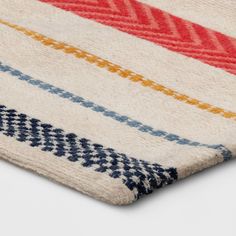 a multicolored striped rug on a white surface with an orange, blue, yellow and red stripe