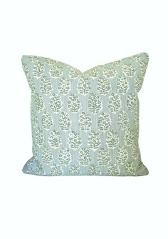 a blue and white pillow with green leaves on the front, against a white background