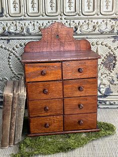 an old wooden dresser with moss growing on the floor next to it and two books