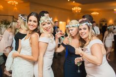 three beautiful young women standing next to each other at a formal event with people in the background