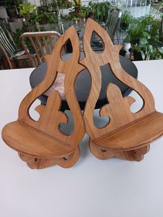 three wooden chairs sitting on top of a table next to each other in front of a potted plant