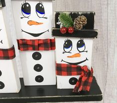 three snowmen with hats and scarves are sitting on a shelf