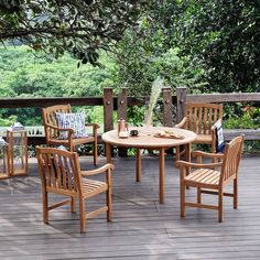 an outdoor table and chairs on a wooden deck with trees in the backround