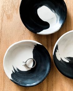 three black and white bowls with rings in them on a wooden surface, top view