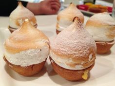 four pastries are sitting on a white plate with powdered sugar and icing