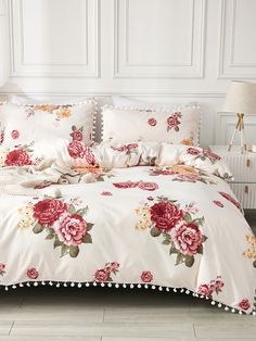 a white bed with pink flowers and pom poms on the pillowcases