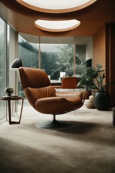 a chair and table in a room with large glass windows on the wall, along with potted plants