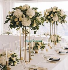 there are many tall vases with white flowers on the table at this wedding reception