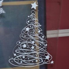 a christmas tree drawn on the side of a window with white stars and swirls