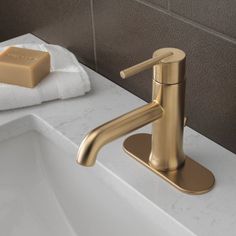 a gold faucet sitting on top of a bathroom sink next to a soap dispenser