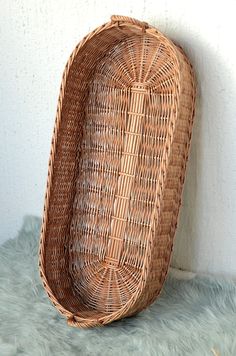 a large wicker basket sitting on top of a green rug next to a white wall