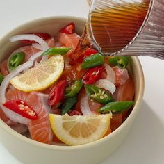 a bowl filled with fish and vegetables being drizzled on top of it