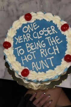 a woman holding up a cake that says one year closer to being the hot rich aunt