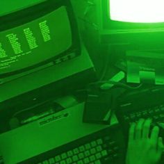 a person typing on a keyboard in front of a tv with green light coming from the screen