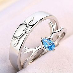 two silver rings with blue stones in them on a white surface, one has an oval shaped