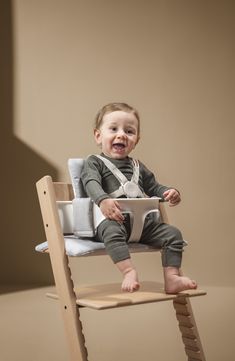 a baby sitting in a wooden high chair with a white bib on it's chest