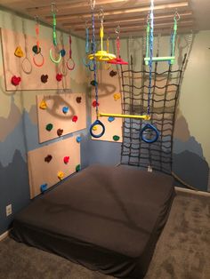 an indoor play area with climbing ropes and toys hanging from the ceiling, in a child's room