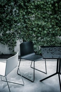 two black and white chairs sitting next to each other near a table in front of a green wall