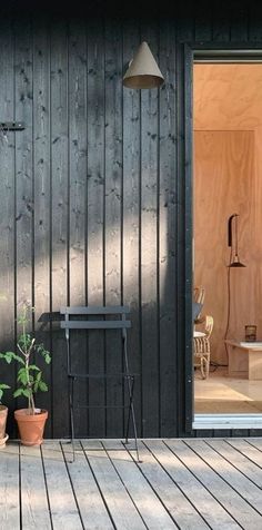 a wooden deck with potted plants on it and an open door to the outside