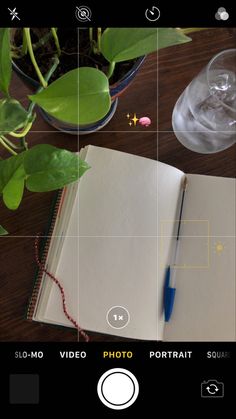 an open book sitting on top of a wooden table next to a glass filled with water