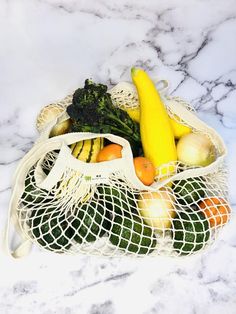 a bag full of fruits and vegetables sitting on a marble counter