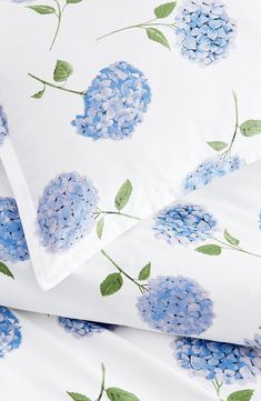 blue hydrangeas on white sheets and pillowcases with green leafy leaves