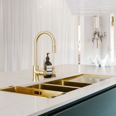 a kitchen sink with gold faucet and soap dispenser