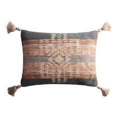 an orange and grey pillow with tassels on the front, sitting on a white background