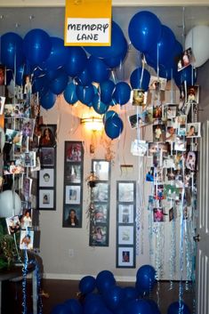 blue balloons and photos are hanging from the ceiling in front of a family memory wall