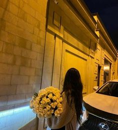 a woman walking down the street with flowers in her hand and a car parked next to her