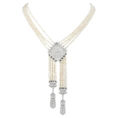 This exquisite Tassel Desing Necklace brings 1920s looks to the modern world.  A dance of cream tone 3 mm, genuine pearls, adorn the piece and the multiple strands.  An Art Deco-inspired Clasp, bow-inspired accents & center filigree pendant, are covered in diamonds, and made in solid 18K White Gold. The center of the filigree pendant has a Round cut Bezel set diamond of approximately 0.20 carats, & the rest of the diamonds in the pendant and two tassels, and its clasp are set with approx. 320 Round cut Diamonds in the metal piece, add brilliance and weigh collectively approximately 2.70 carats in total H-I  color and VS clarity Secured with an 18K Gold, diamond-accented Insert Clasp. The clasp/Pendant  measures approximately 32 mm x 32 mm, 4.5" Drop And the total length is 21.5" long. Rema Luxury White Gold Art Deco Necklace, Art Deco Jewelry 1920s, 1920s Necklace, Pearl And Diamond Necklace, Long Pearl Necklaces, Jewelry Appraisal, Filigree Pendant, Art Deco Necklace, Tassel Jewelry