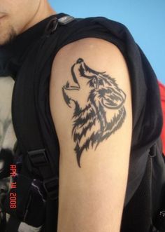 a man with a wolf tattoo on his arm and shoulder is looking at the camera