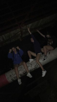 three people sitting on top of a fire hydrant in the dark with their arms up