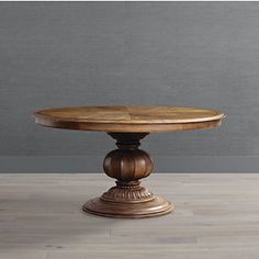 a wooden table sitting on top of a hard wood floor next to a gray wall