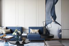 a living room with blue couches and art work on the wall behind each sofa