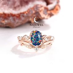 an opal and diamond ring sits on top of a piece of jewelry next to a rock