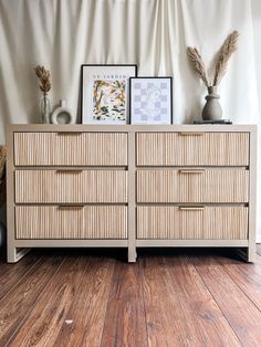 a dresser with two drawers and pictures on top of it in front of a curtain