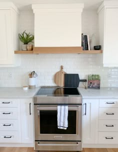 a kitchen with white cabinets and stainless steel stove top oven in the center, surrounded by wooden shelves