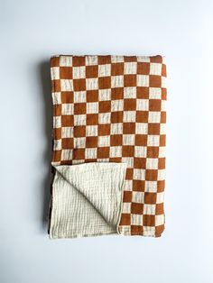 a brown and white checkered blanket laying on top of a table