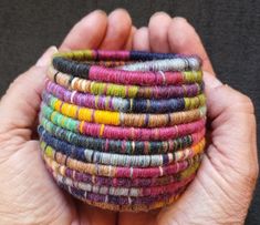 a hand holding a stack of multicolored bracelets