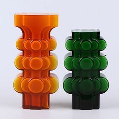 two colorful vases sitting next to each other on a white surface with no one around them