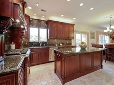 a large kitchen with granite counter tops and wooden cabinets, along with marble flooring