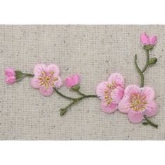 some pink flowers are on the side of a piece of fabric with green stems and leaves