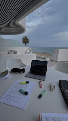 an open laptop computer sitting on top of a table next to a book and pen