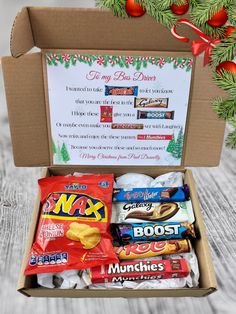 an open box filled with candy on top of a wooden table next to a christmas tree